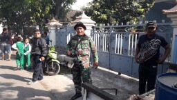 Anggota Koramil 0816/09 Krian dampingi warga Desa Tropodo Krian adakan penyemprotan DBD.