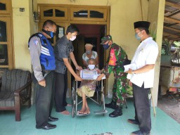 Babinsa Koramil 0816/12 Prambon bersama Babinkamtibmas dampingi Pemdes menyalurkan BLT Dana Desa ke warga kurang mampu